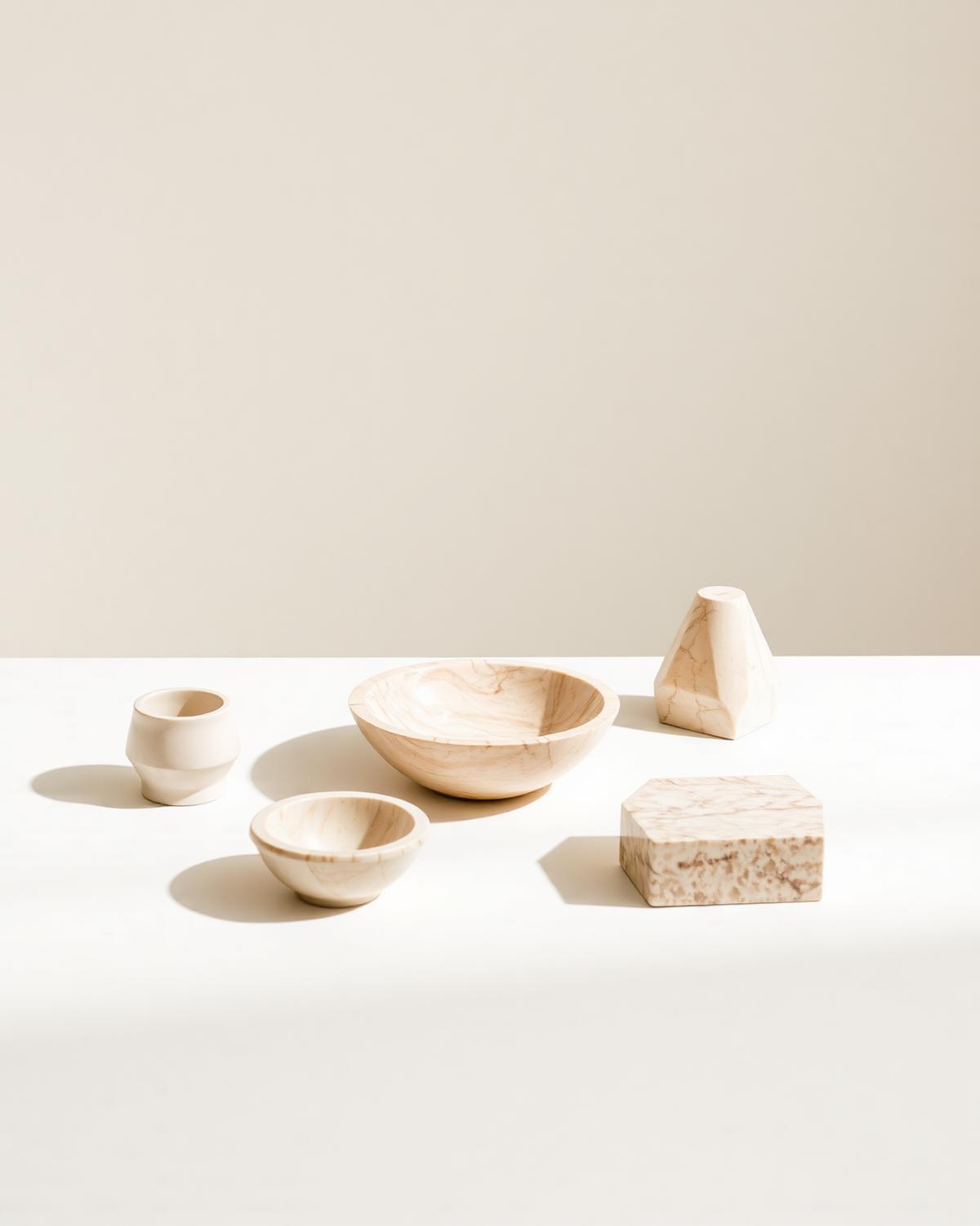 Objetos decorativos em pedra natural bege sobre superfície clara